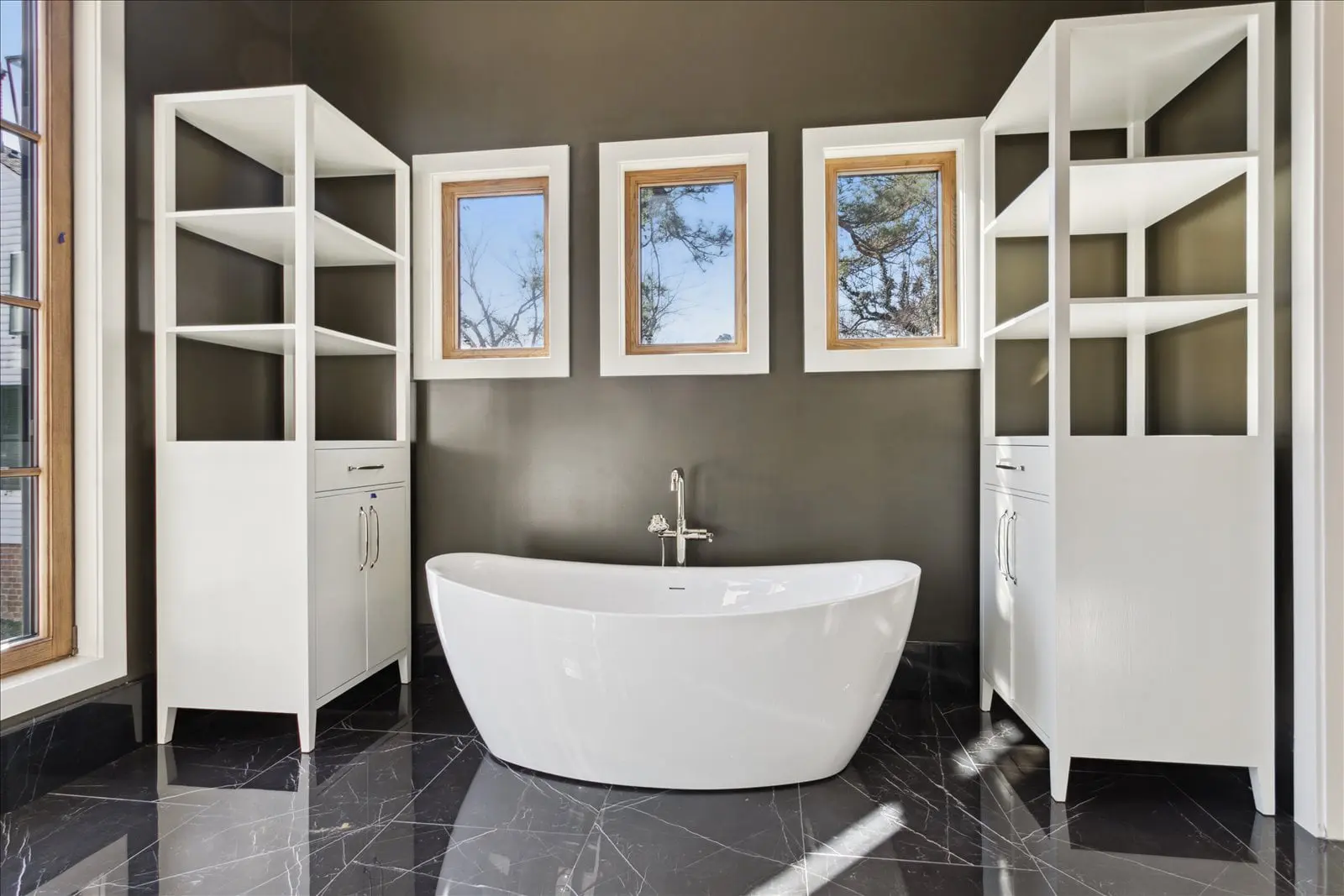 Finished BAC bathroom with freestanding tub, built-in storage, and dark stone flooring